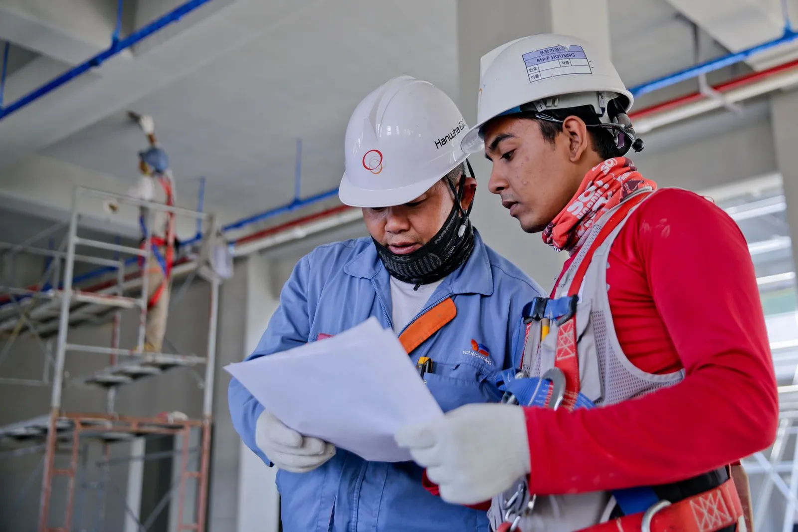 Two engineers in hard hats reviewing a set of plans on a job site