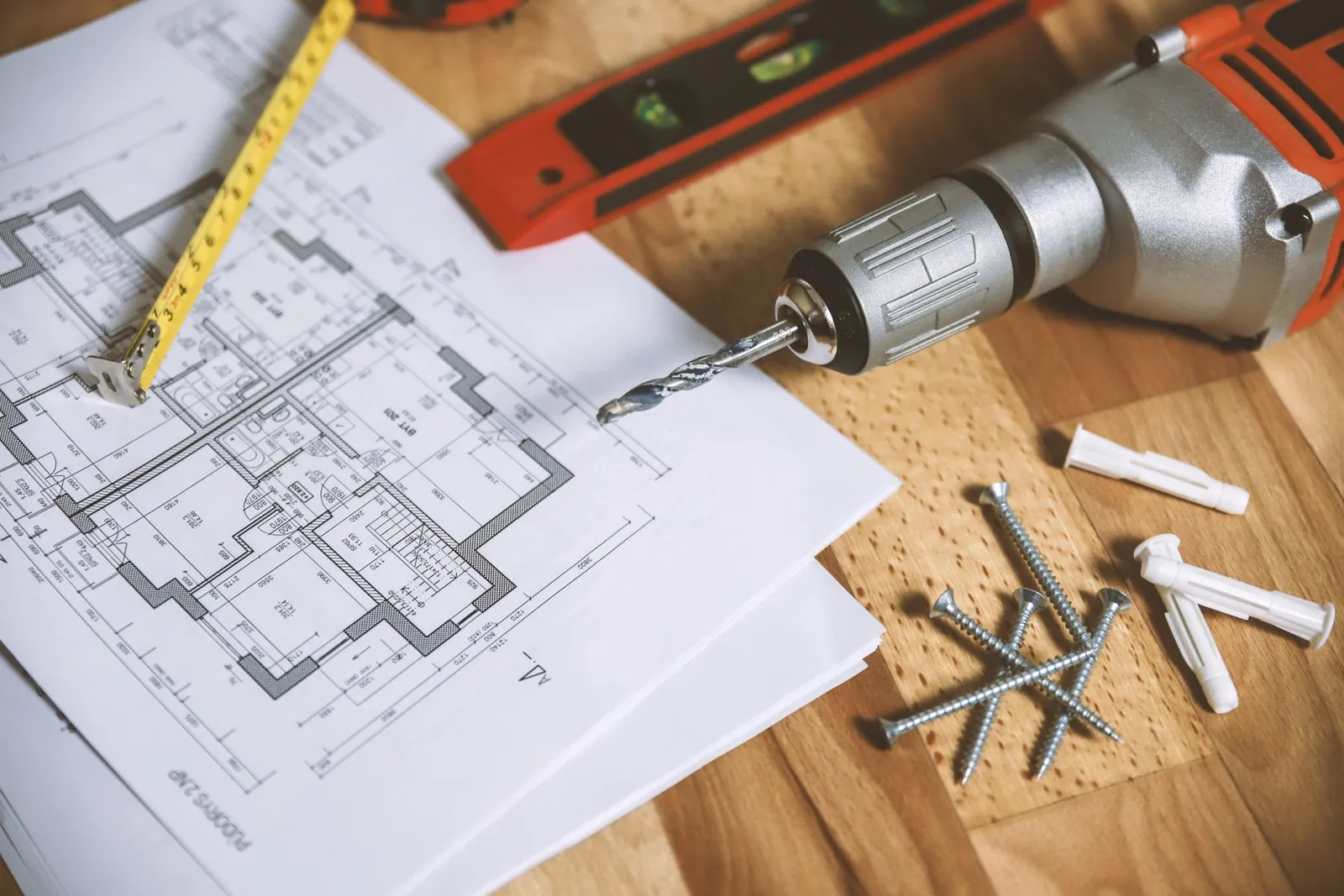 Floor plans on a workbench with a level, drill and tape measure
