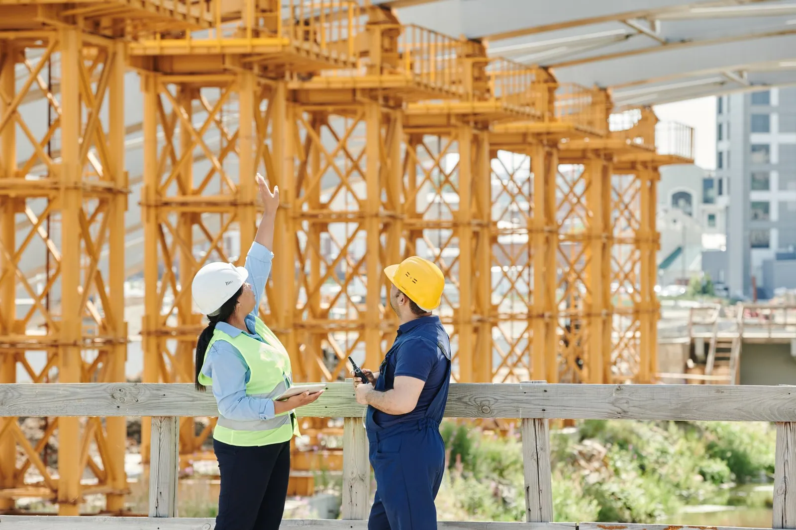 Two construction professionals in hard hats talking on a building site